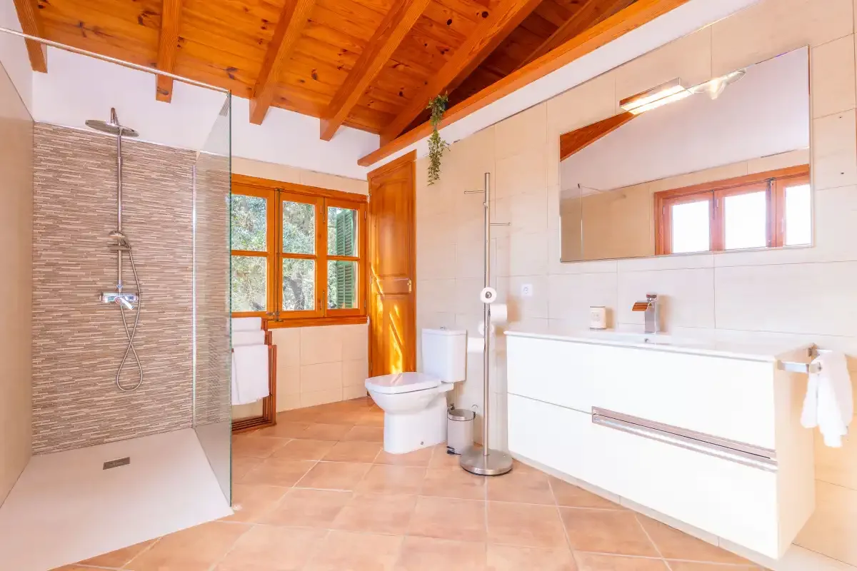 Un baño luminoso con ducha de vidrio, bañera y un largo lavabo.