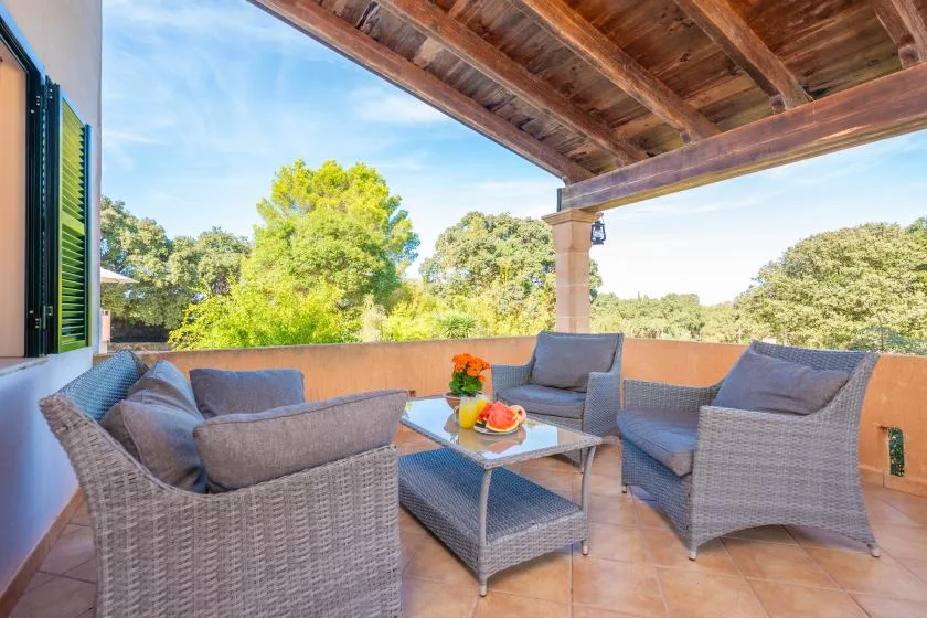 Una zona de estar exterior cubierta con asientos de mimbre alrededor de una mesa pequeña.