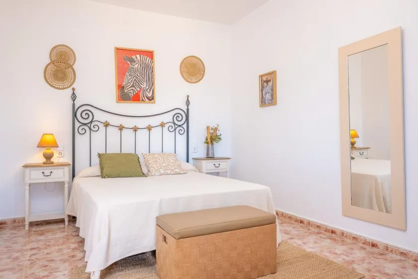 Un dormitorio luminoso con una cama blanca, un cabecero decorativo y mesitas de noche.