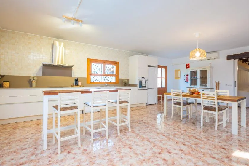Una cocina luminosa con zona de comedor, una encimera larga y una mesa.
