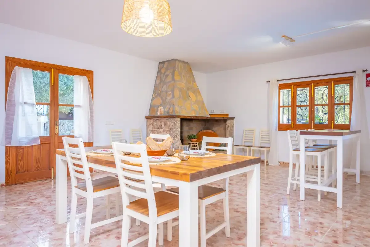 Comedor con asientos blancos y una chimenea de piedra.