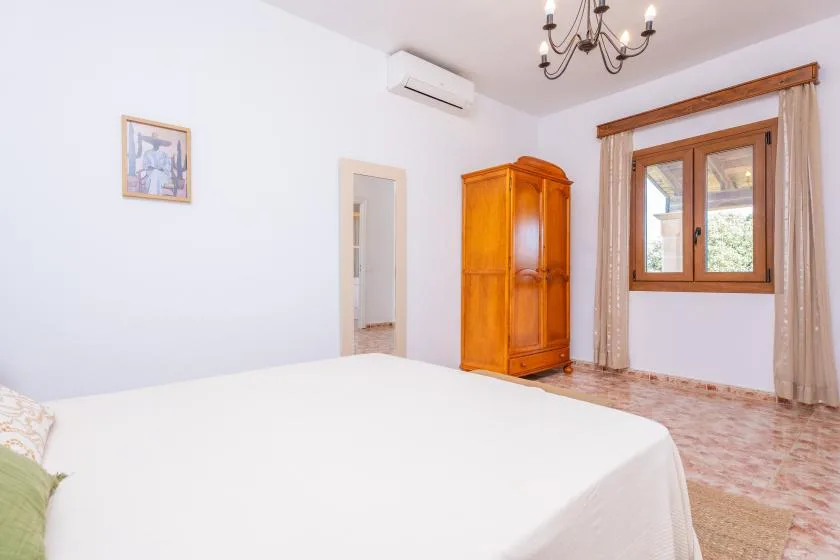Un dormitorio con una cama grande, un armario de madera y una ventana.