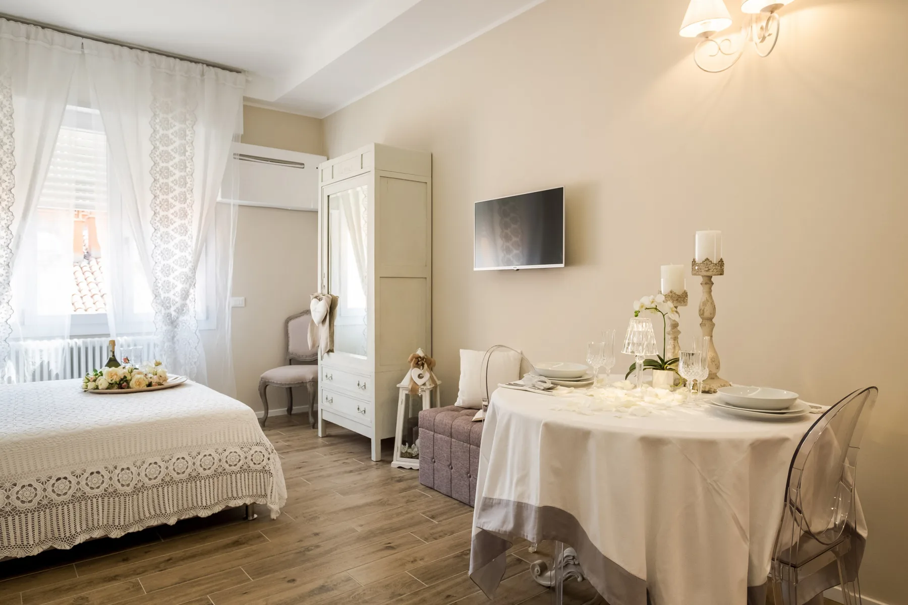Un dormitorio y una zona de comedor comparten una habitación luminosa, con una cama junto a una mesa puesta.