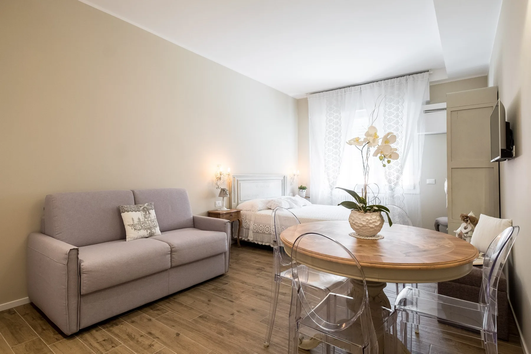 Una luminosa estancia con sofá, cama y una mesa de comedor redonda.