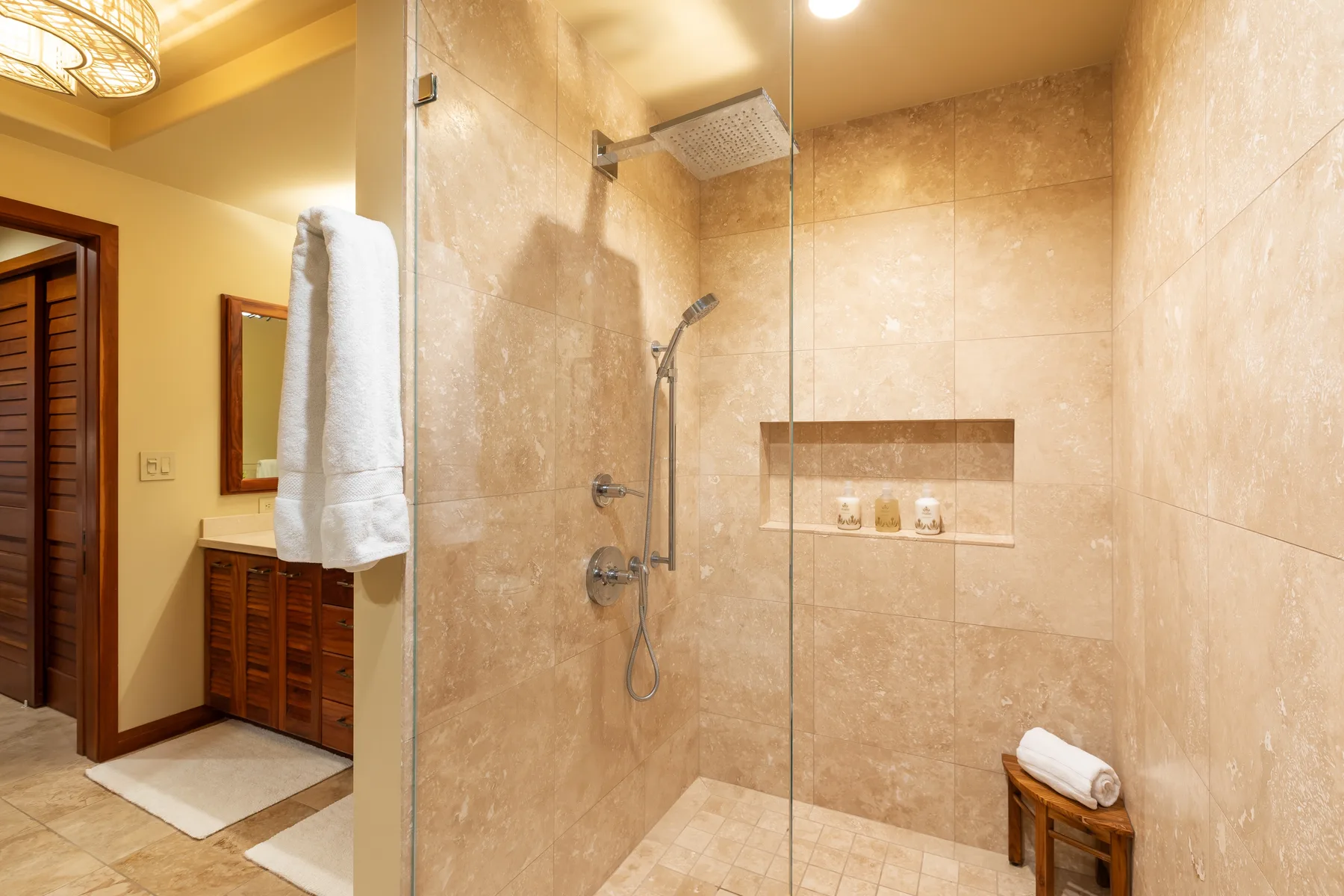 Una ducha de baño con azulejos, ducha de mano y estante empotrado.