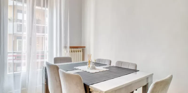 A dining area with a table set beside tall windows.