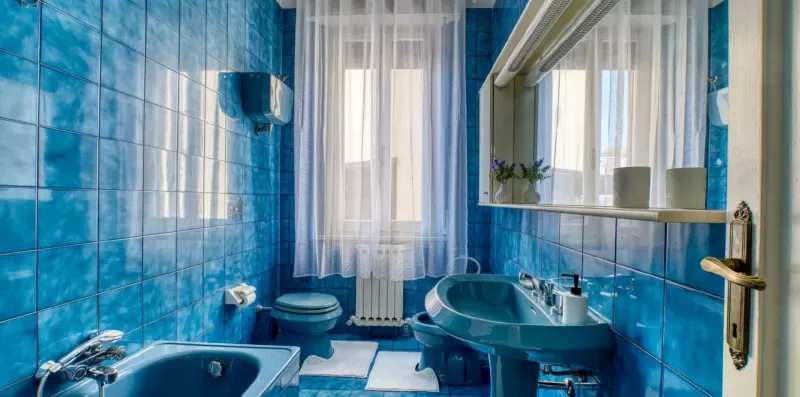 A bathroom with blue tiled walls, a bathtub, and a sink.