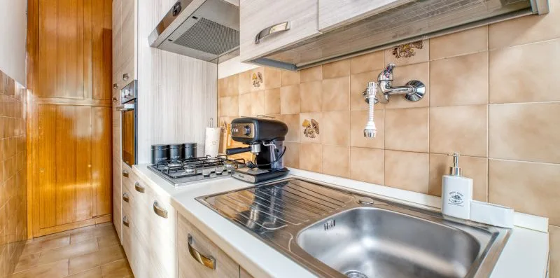 A kitchen counter with a stovetop, coffee maker, and sink.