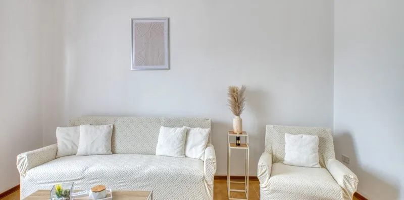 A bright living room with two light-colored seating pieces and a small side table.
