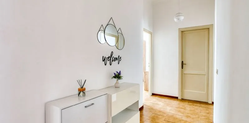 A bright hallway with a closed door, tiled floor, and a small console.