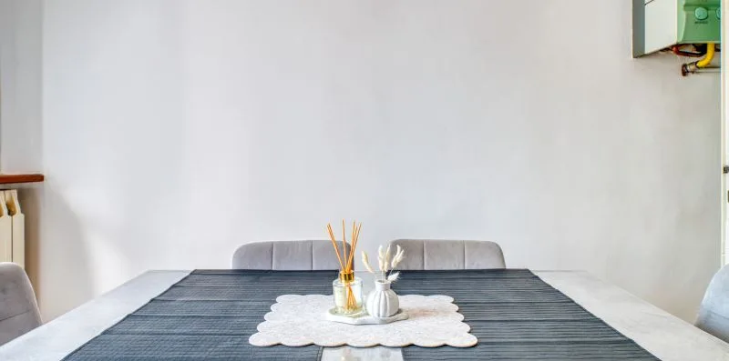 A dining table with a decorative centerpiece sits against a plain white wall.