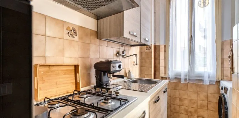 A kitchen with a gas cooktop, countertop appliances, and a bright window.
