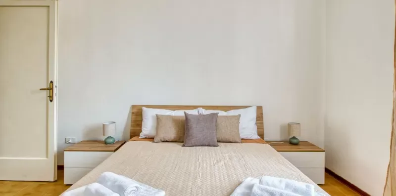 A bedroom with a neatly made bed and small bedside tables.