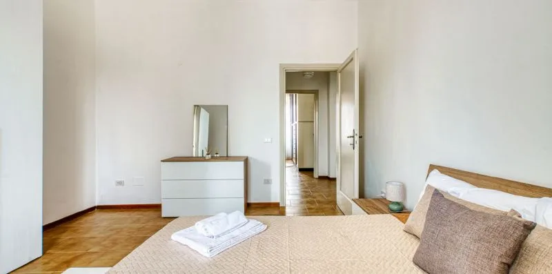 A bedroom with a bed, dresser, and an open doorway.