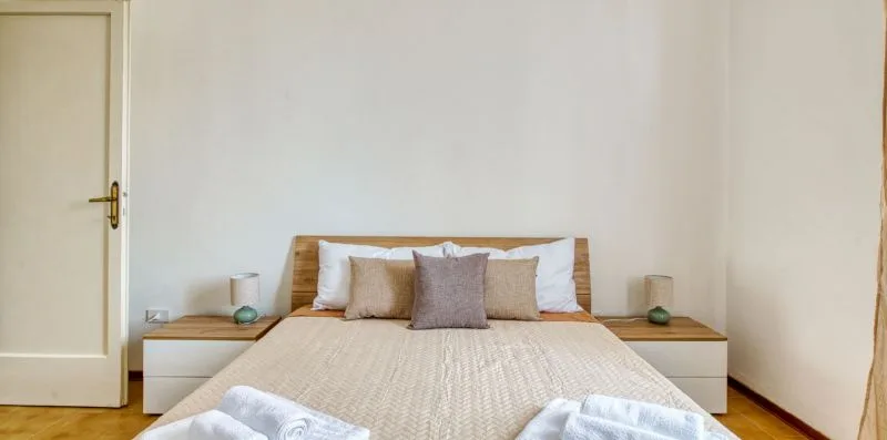 A bedroom with a neatly made bed and small bedside tables.