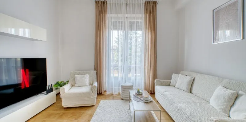 A bright living room with seating arranged around a coffee table and television.