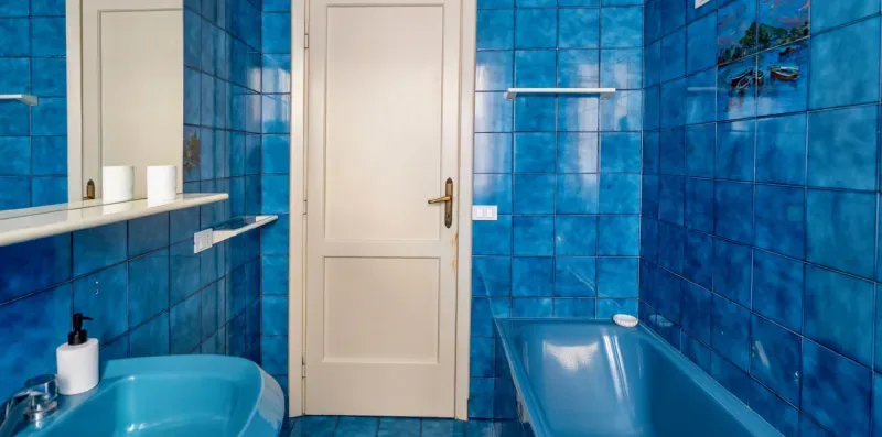 A blue-tiled bathroom with a bathtub and sink.