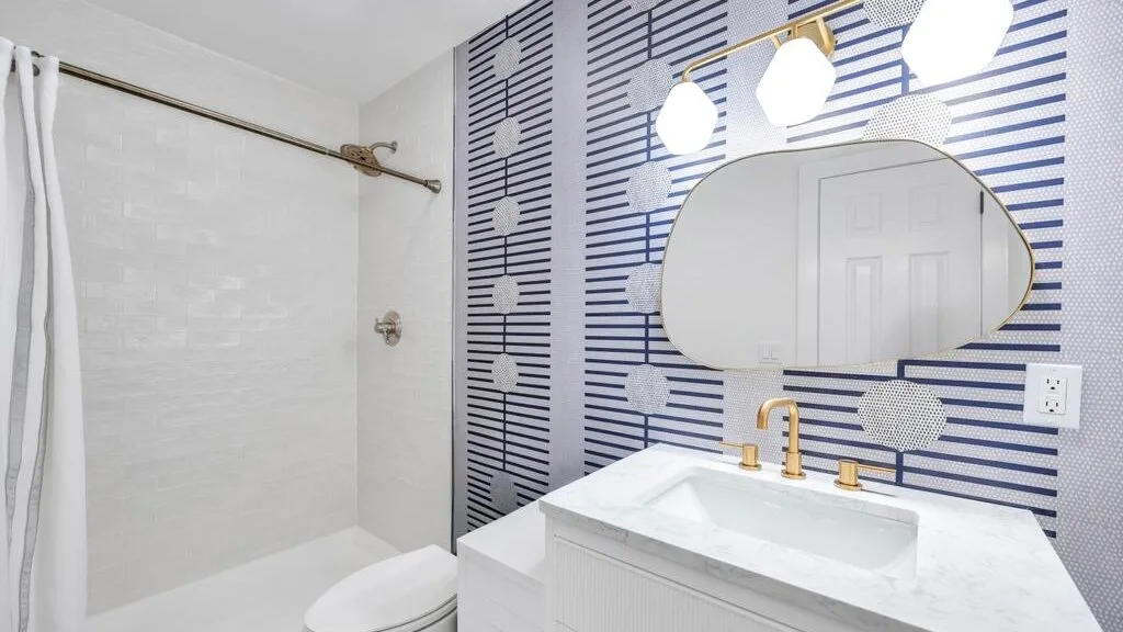 Un baño con ducha, tocador y un espejo grande.