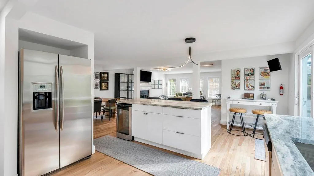 Una cocina luminosa y abierta con una isla central y un refrigerador de acero inoxidable.