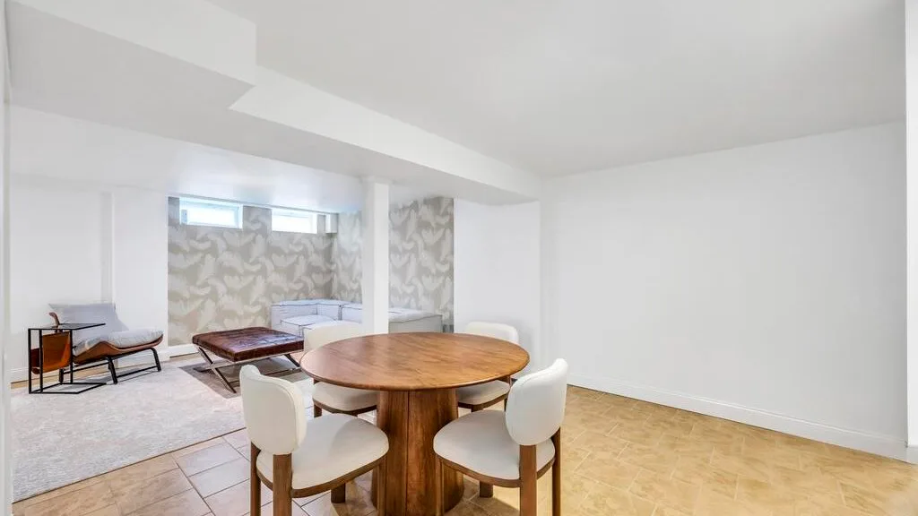 Una luminosa sala de estar y comedor con una mesa redonda de madera y asientos.