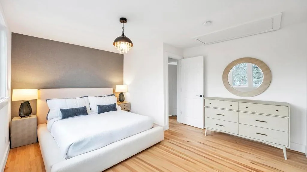 Un dormitorio con una cama, una cómoda y una puerta abierta.