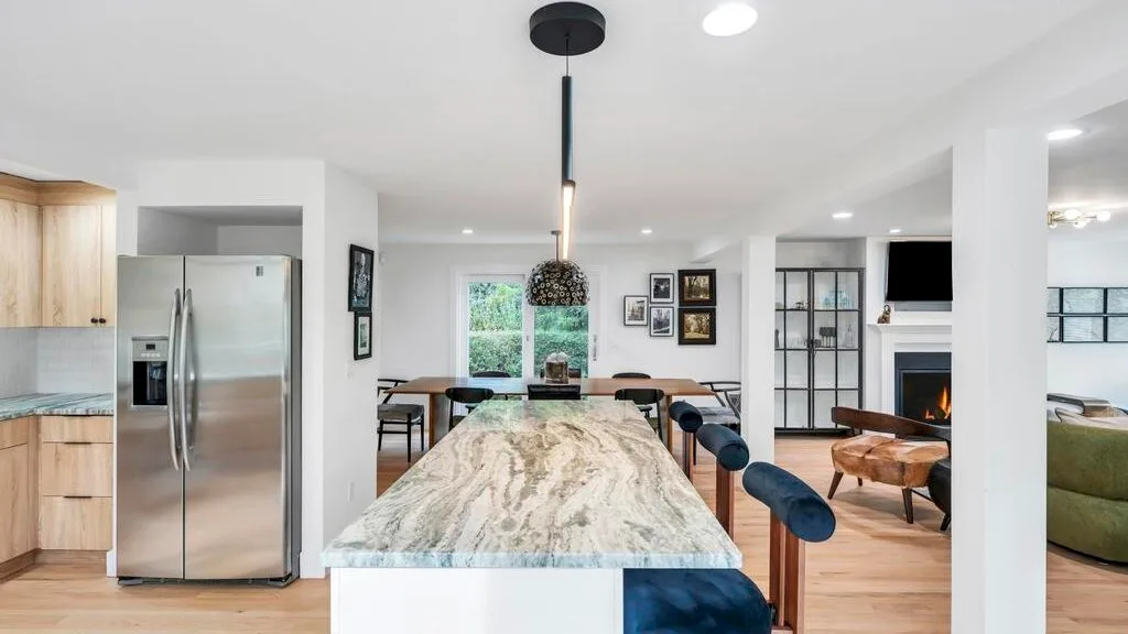 Una cocina y sala de estar de concepto abierto con una isla larga y una mesa de comedor.
