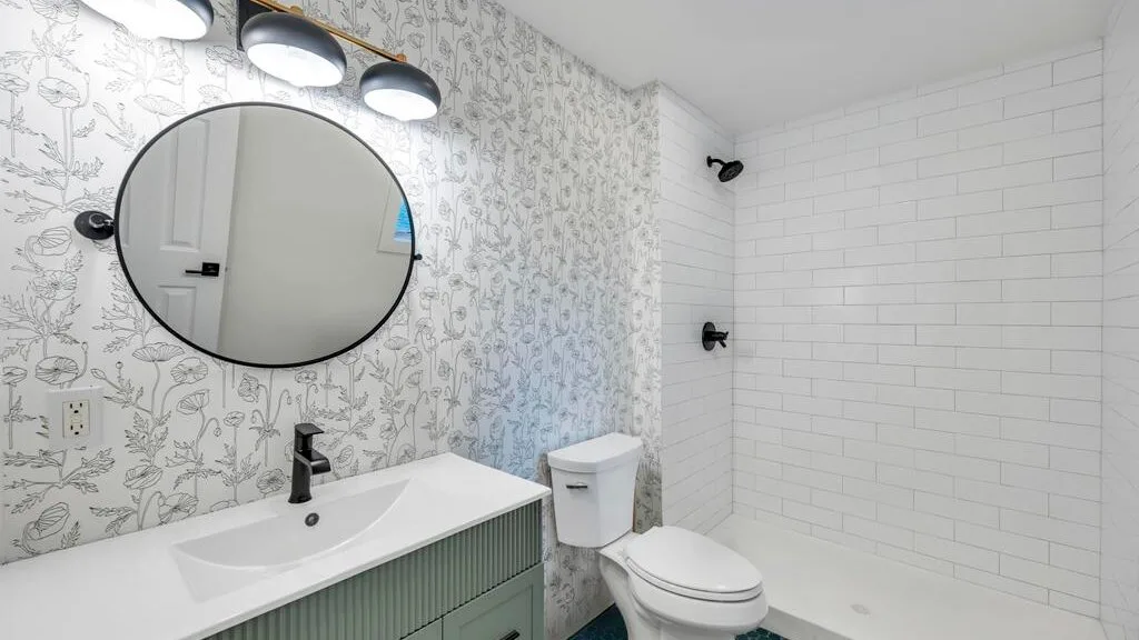 Un baño con lavabo, inodoro y zona de ducha con azulejos.