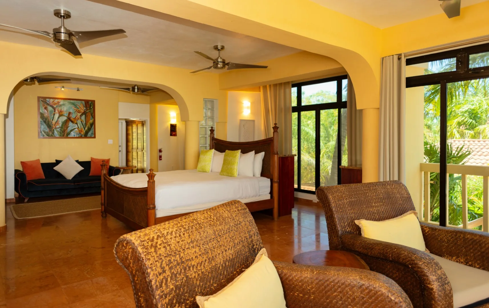 A bedroom with a central bed, seating, and large windows.
