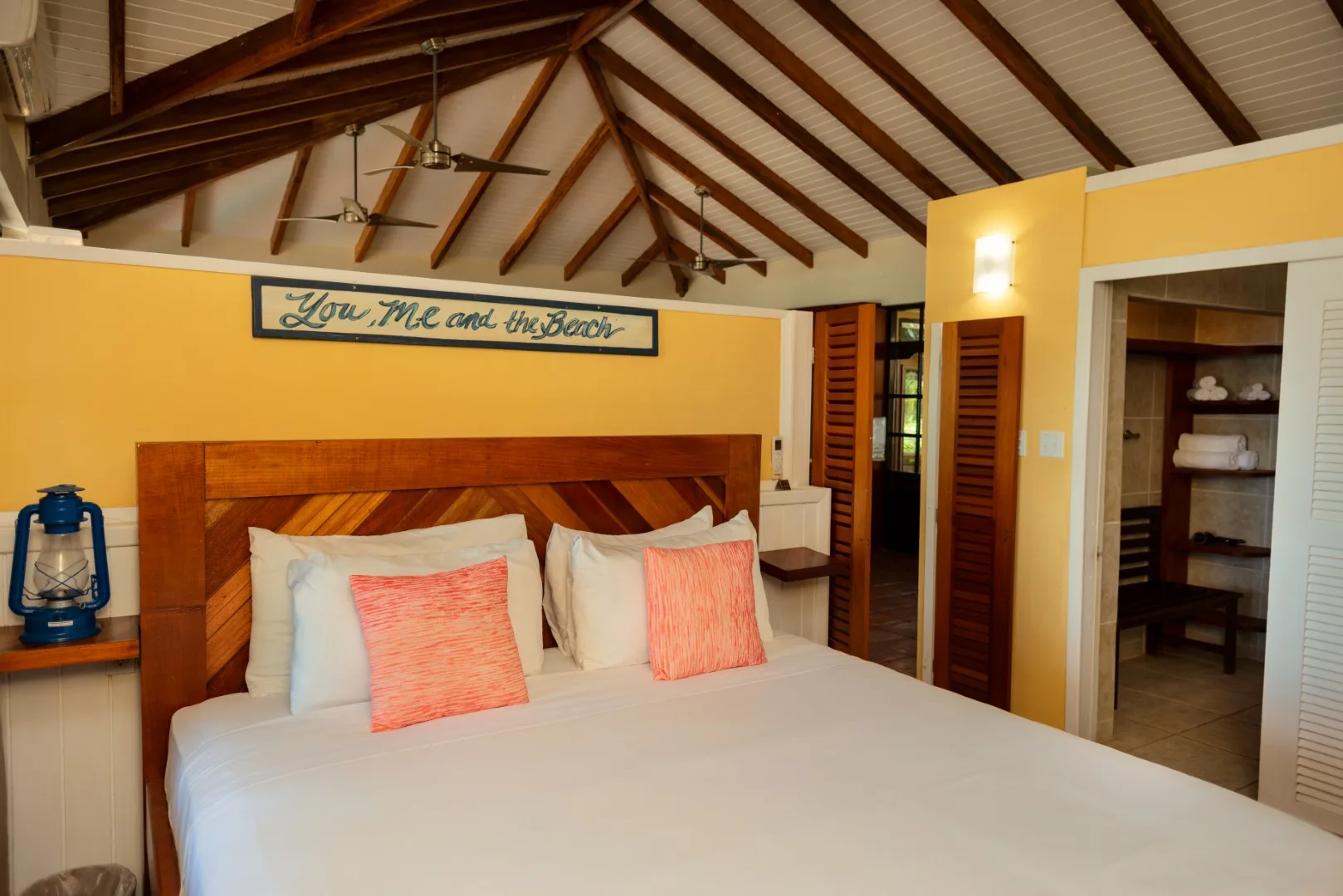 A bedroom with a large bed beneath a high, exposed-beam ceiling.