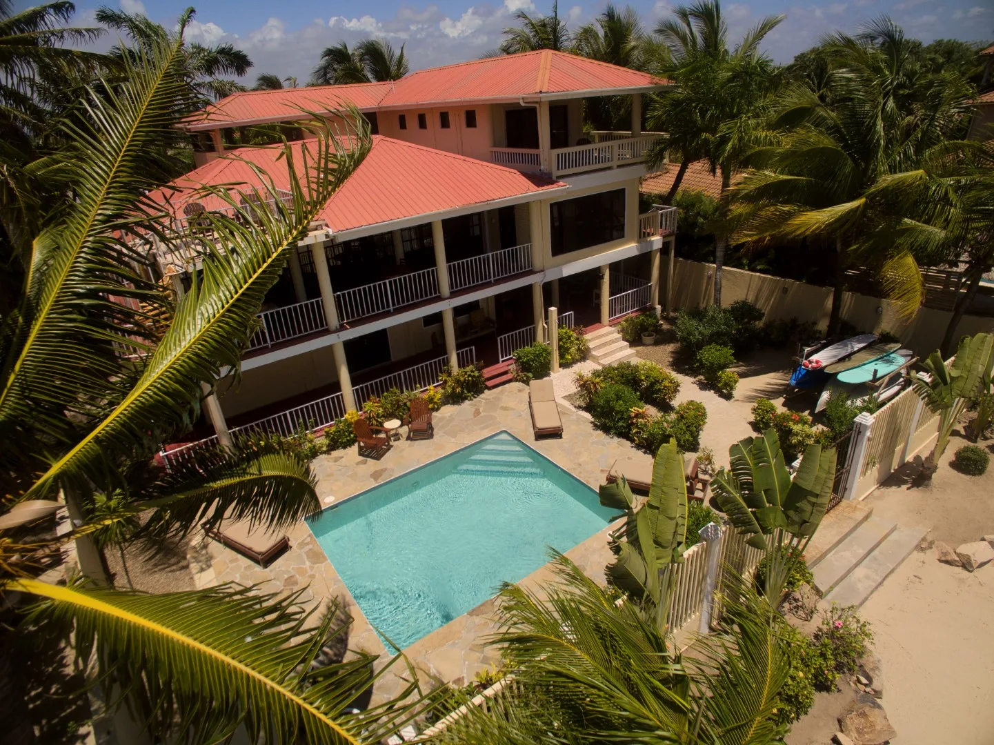 A tropical property with a multi-level building, swimming pool, and palm trees.