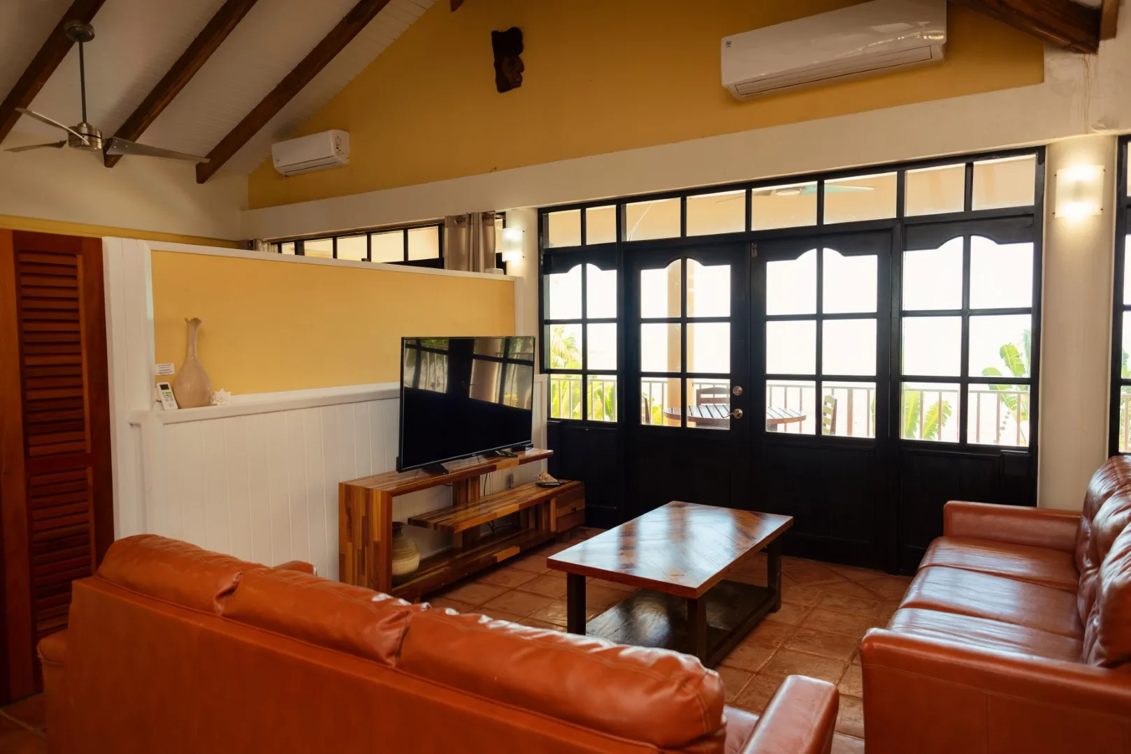 A living room with leather seating, a coffee table, and large windows.