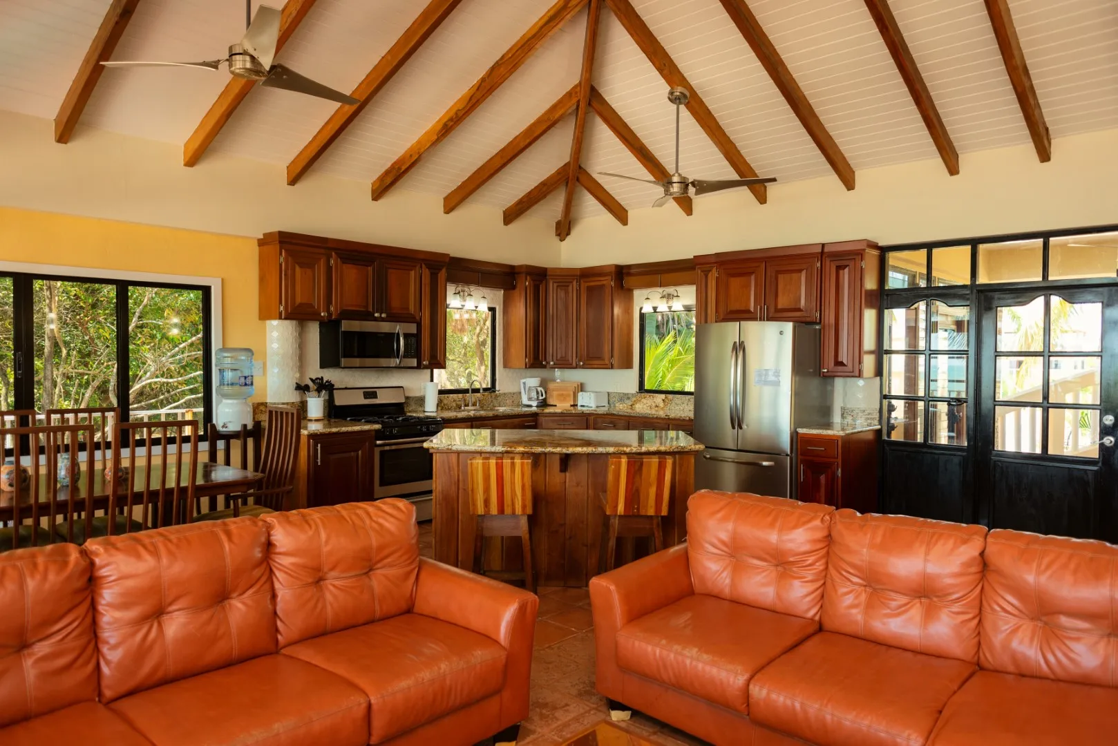 An open-plan living room and kitchen with orange seating and a wooden island.