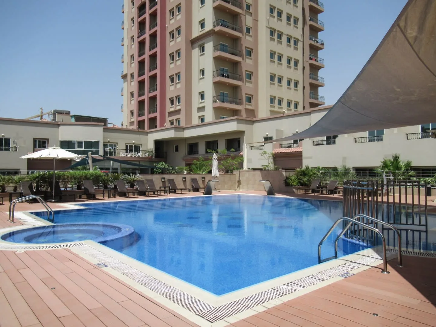Una piscina al aire libre está junto a una terraza con tumbonas.