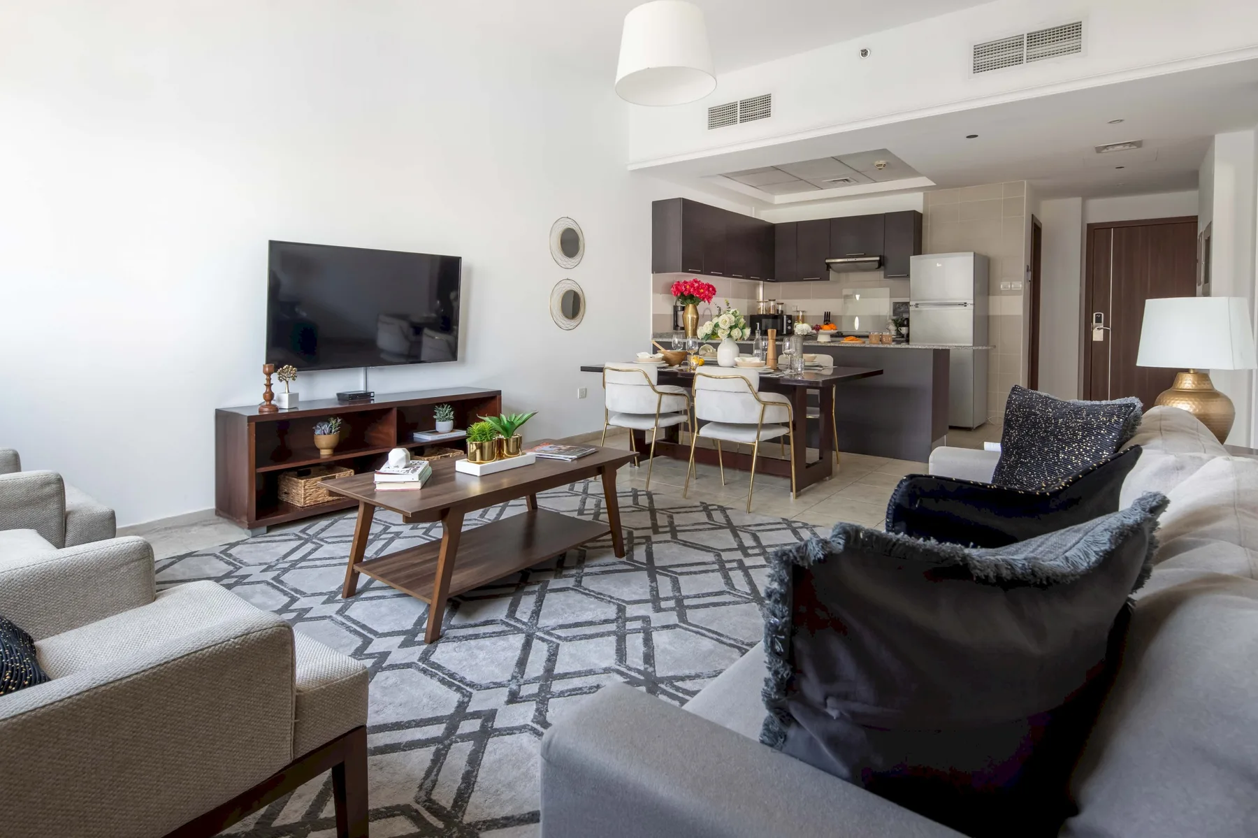 Una sala de estar se abre a una cocina y comedor, con asientos alrededor de una mesa baja.