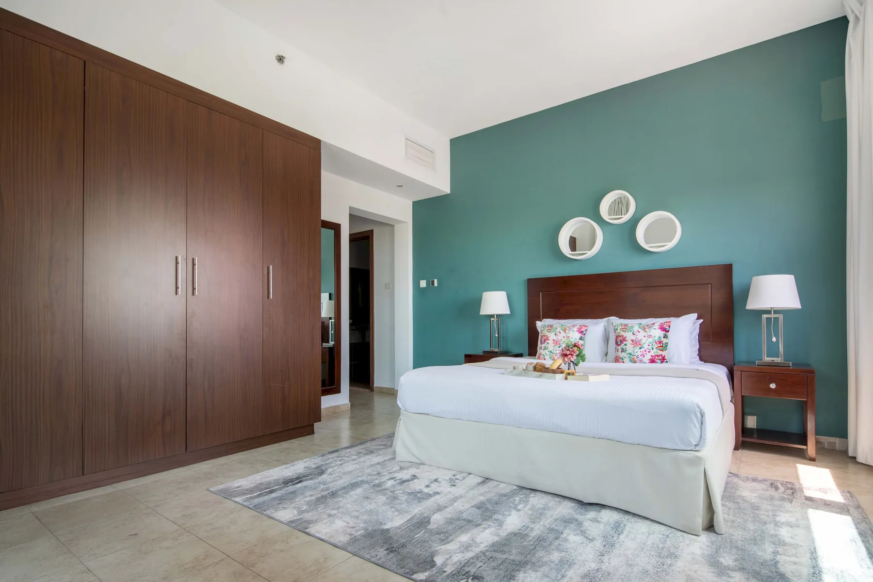 Un dormitorio con una cama, una pared de acento verde azulado y armarios empotrados.
