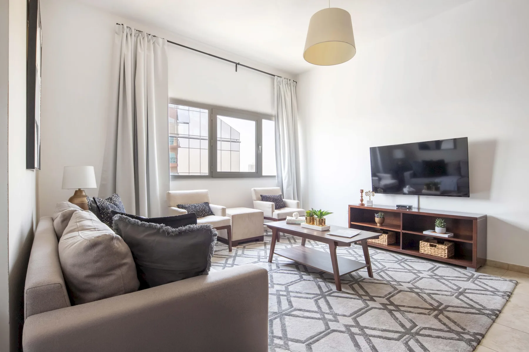 Una sala de estar luminosa con asientos, una mesa de centro y un televisor.