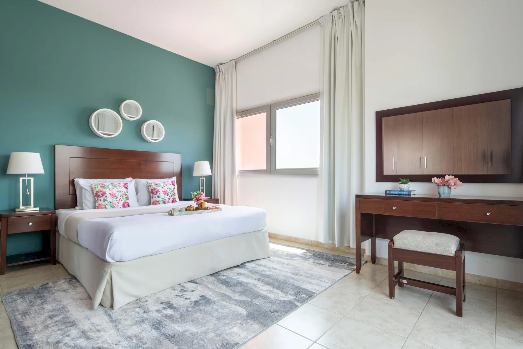 Un dormitorio con una cama tendida, una pared verde azulado y un escritorio.