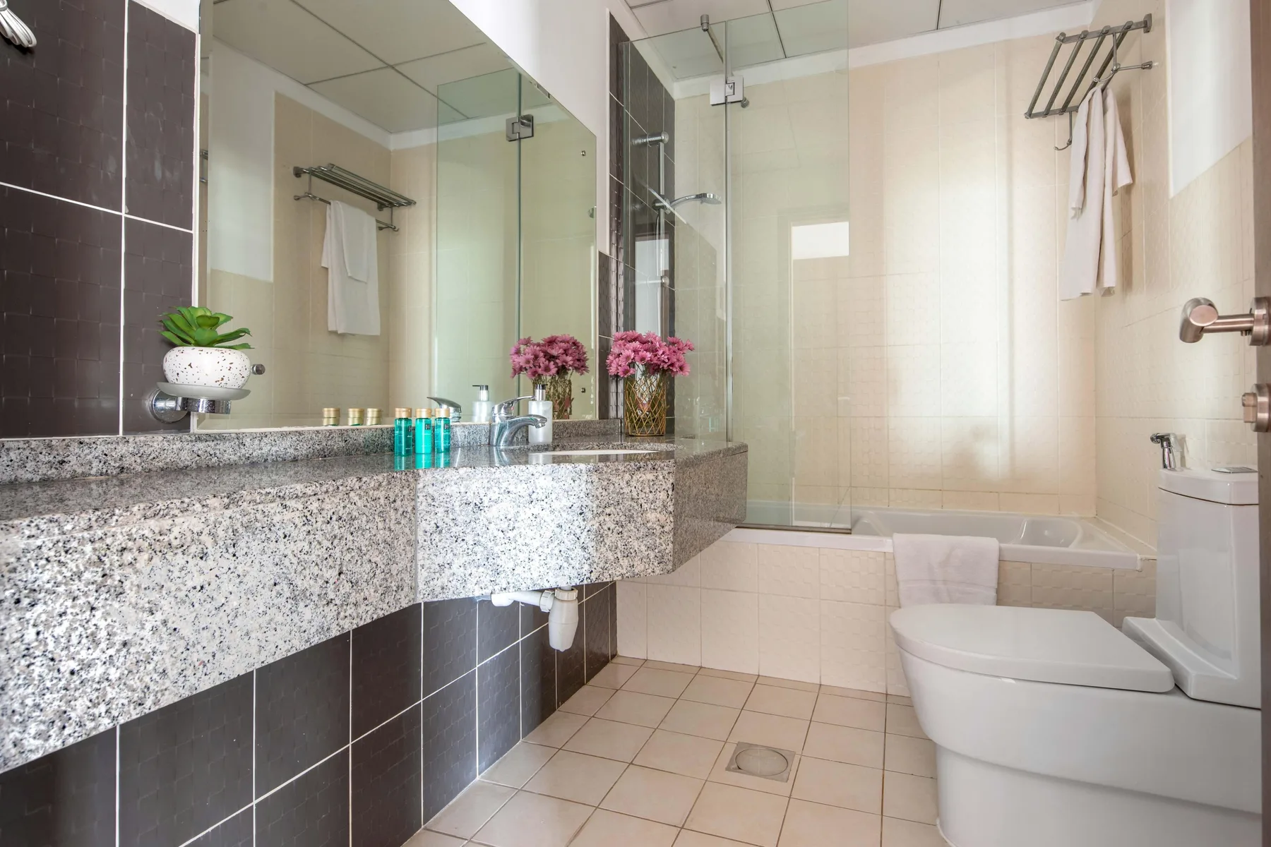 Un baño con azulejos, ducha de vidrio, espejo y encimera de lavabo.