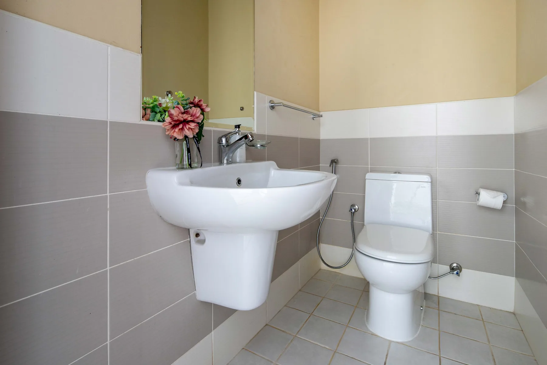 Un baño con lavabo de pedestal, inodoro y paredes de azulejos.