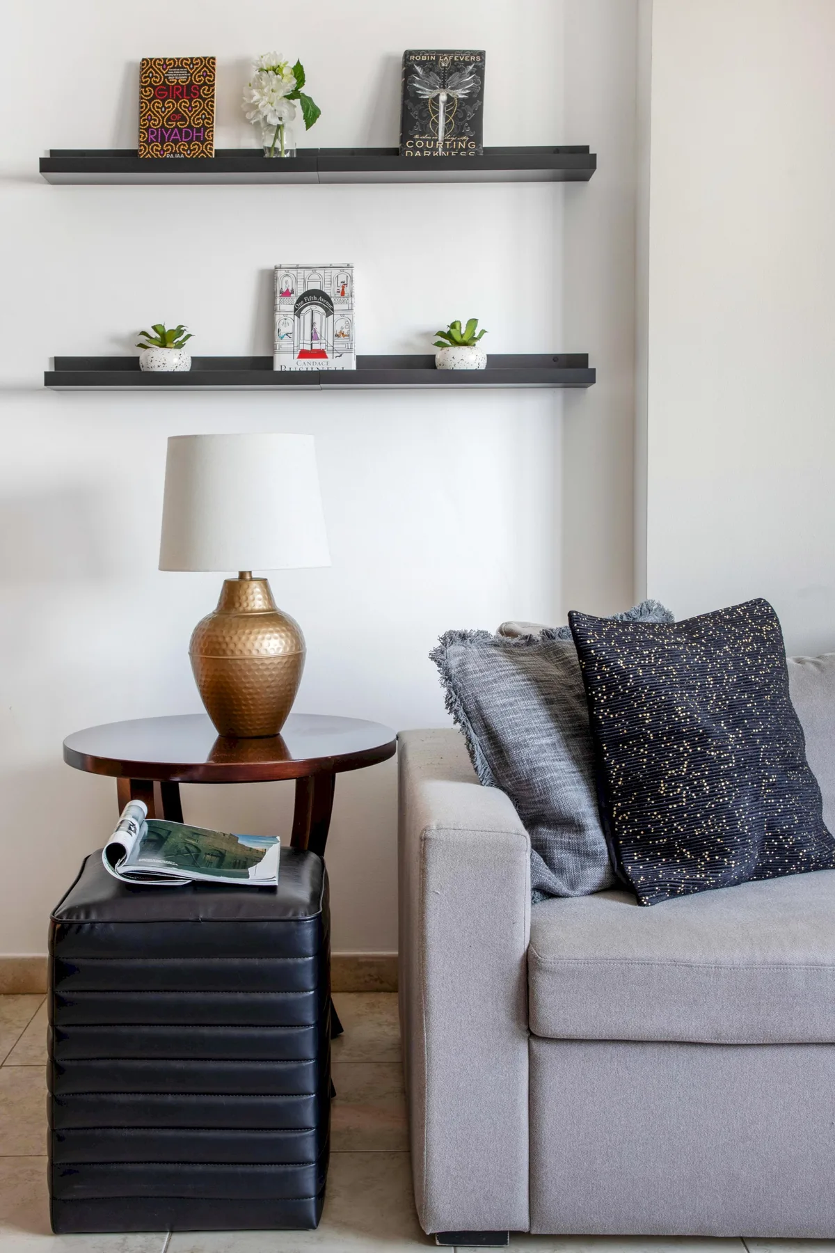 Una zona de estar con una lámpara y libros colocados en estantes de pared.