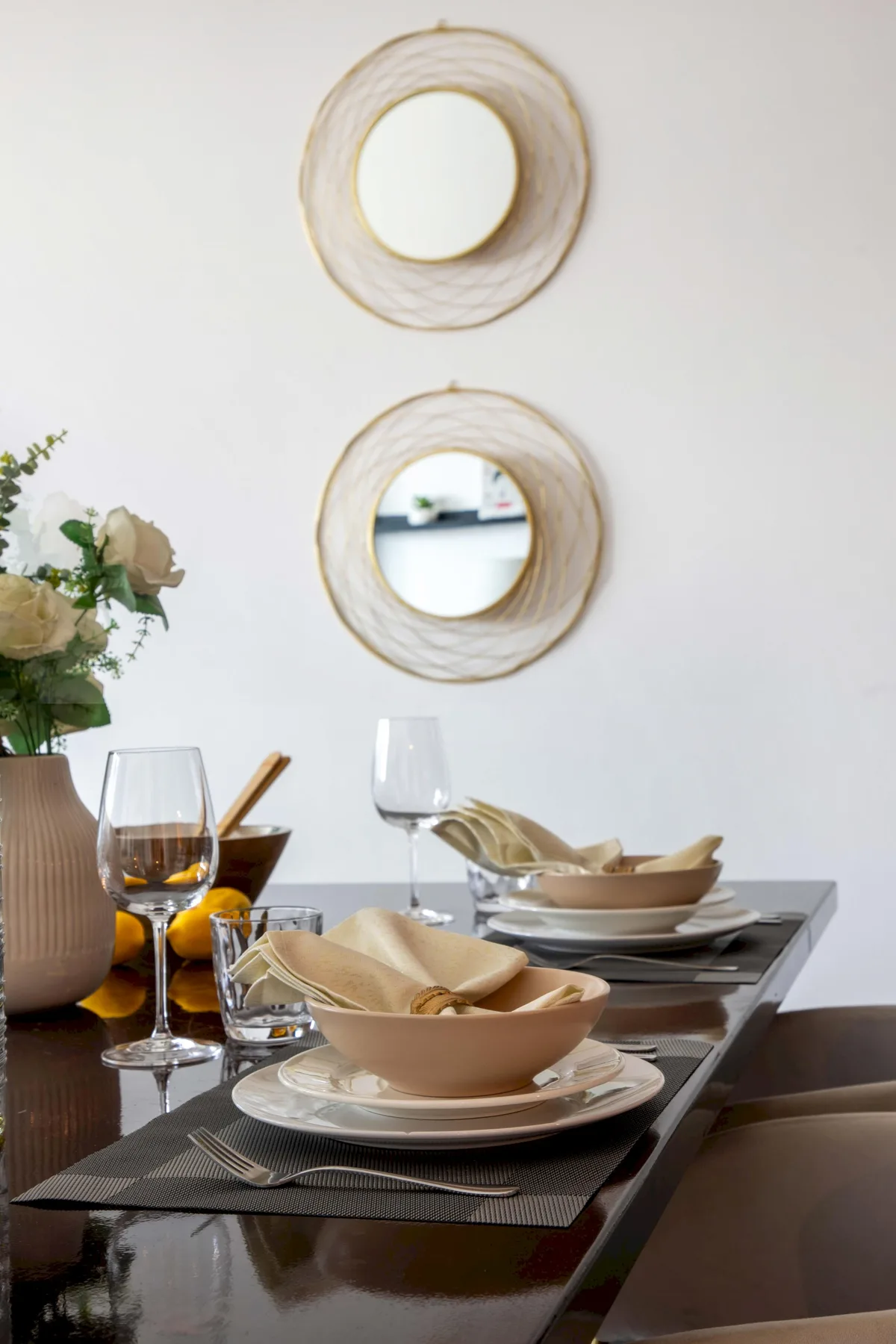 Una mesa de comedor está puesta con platos, cuencos, copas y servilletas dobladas.