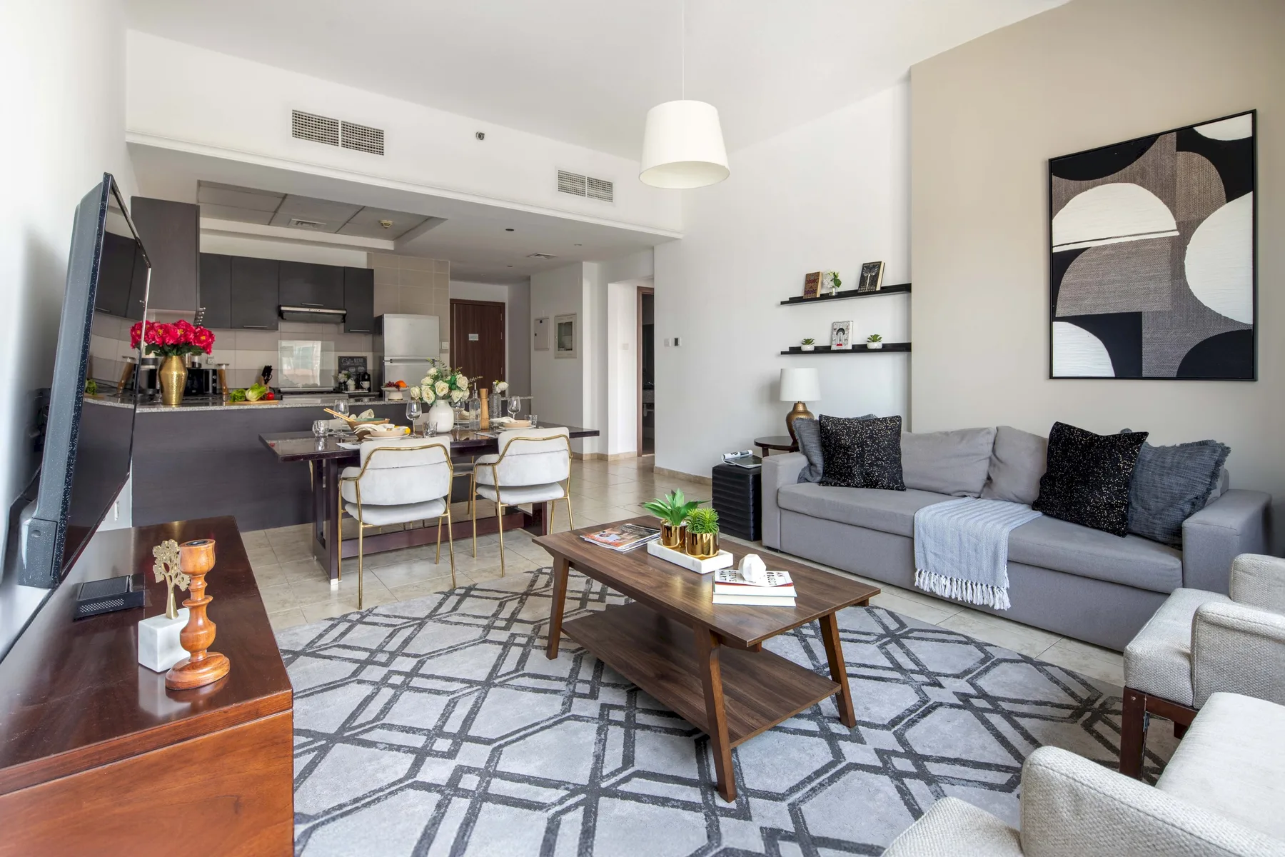 Sala de estar de planta abierta con una zona de asientos gris y mesa de comedor.