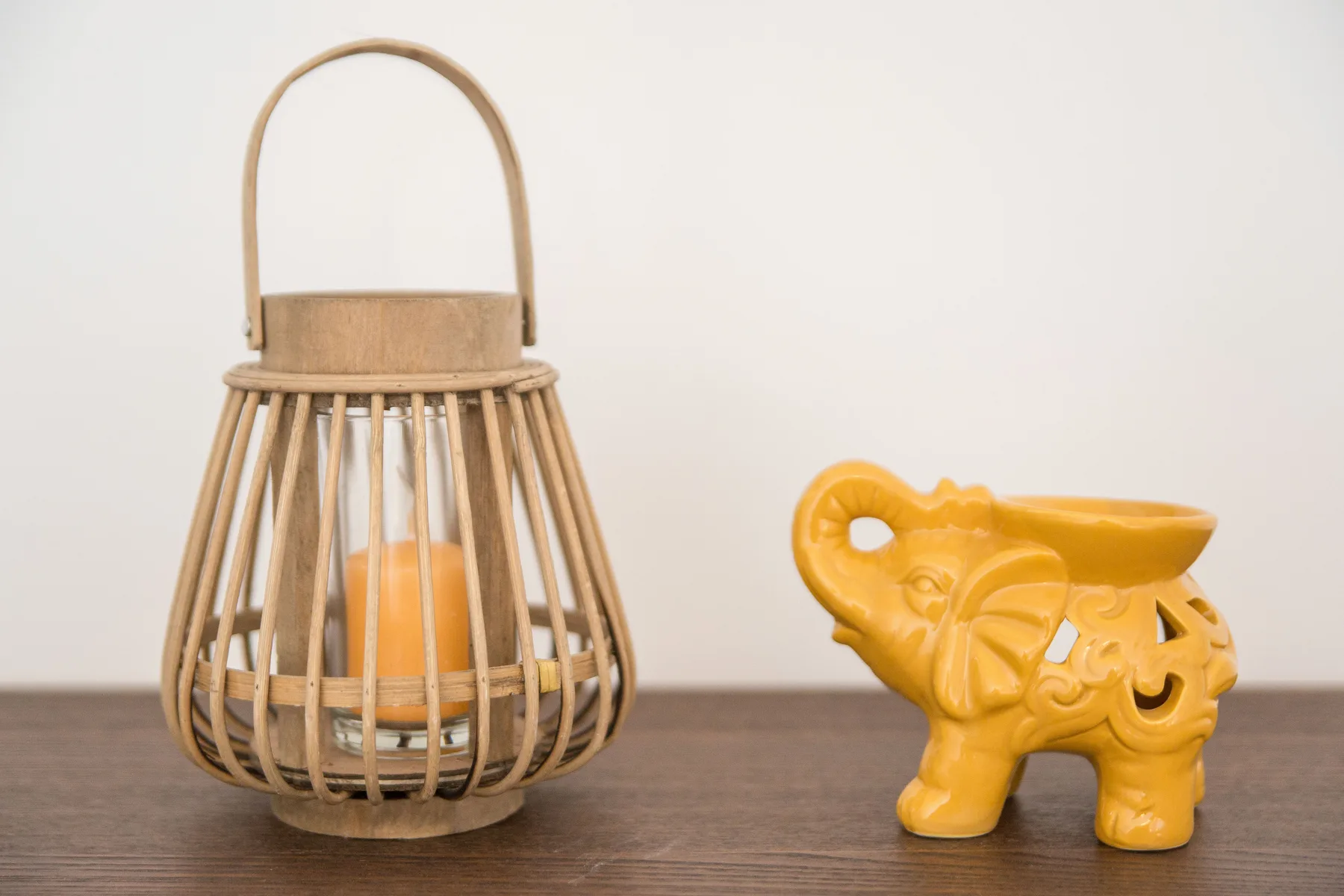 Una decoración sobre una mesa muestra un farol tejido y una pequeña figura de elefante amarillo.