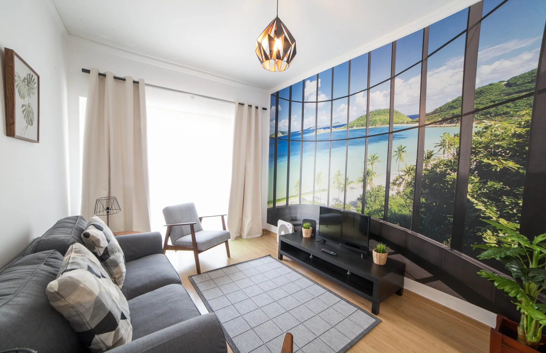 Living room with seating, a television, and a large scenic wall mural.
