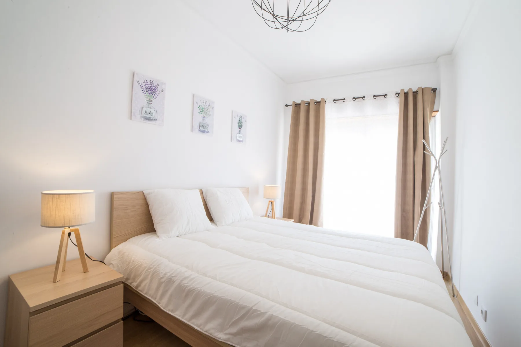 Un dormitorio luminoso con una cama, una mesita de noche y cortinas junto a la ventana.