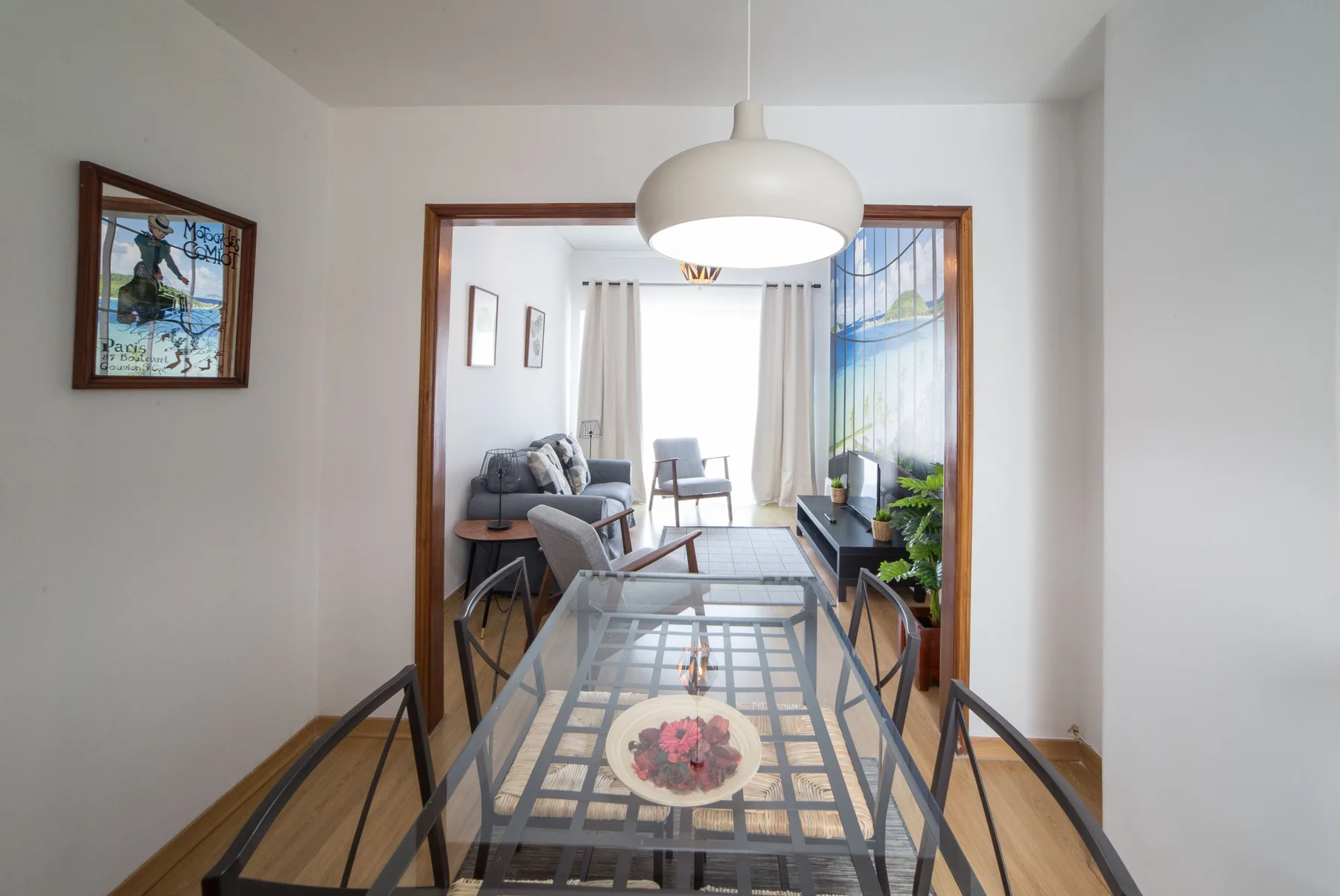 Comedor con una mesa de vidrio y una zona de estar al fondo.