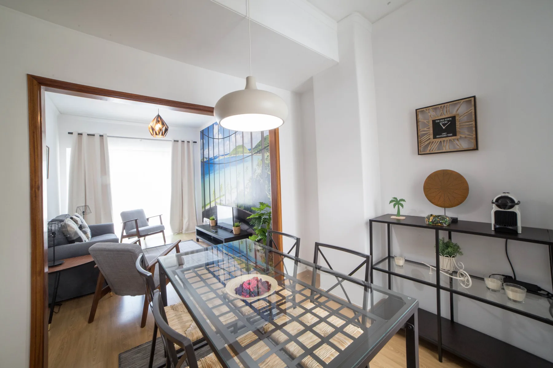 Un comedor con mesa de vidrio y sillas se abre a una luminosa zona de estar.