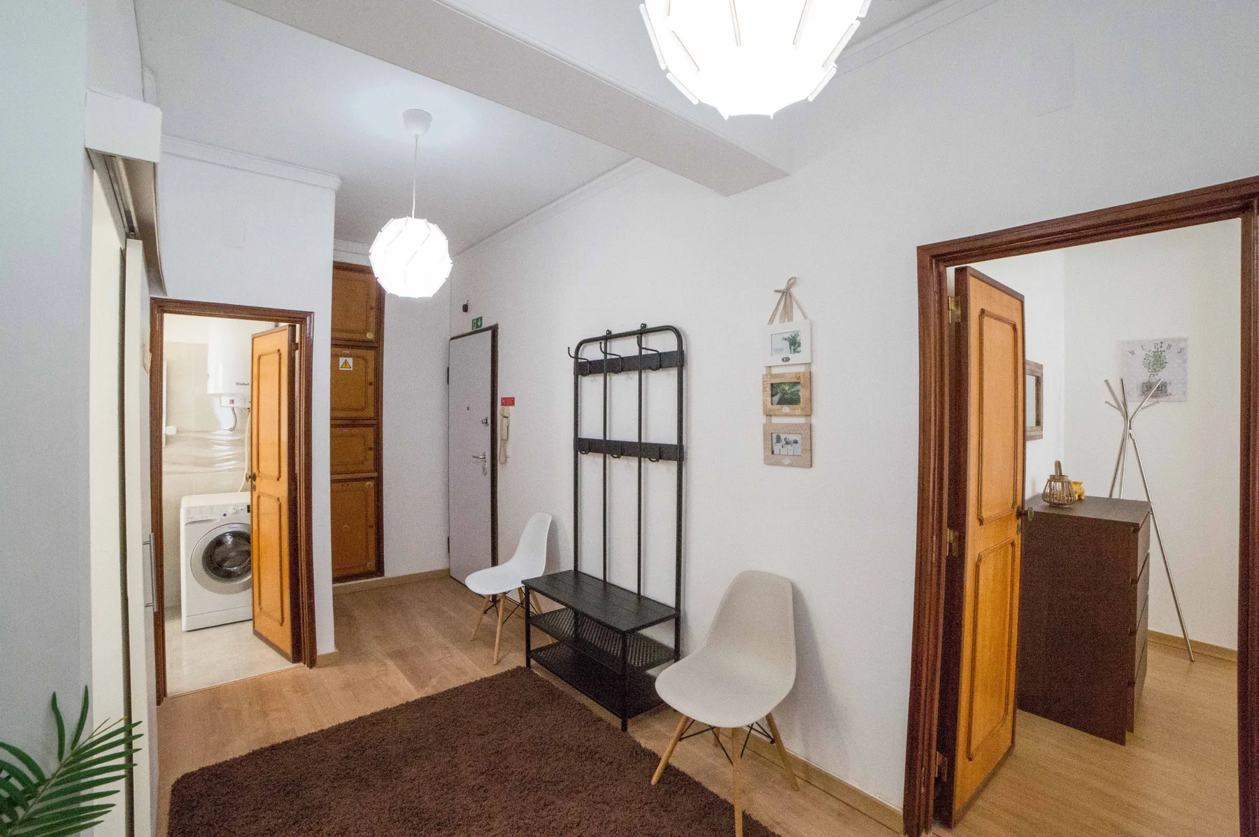 Un recibidor de apartamento con una alfombra oscura, un banco y asientos.