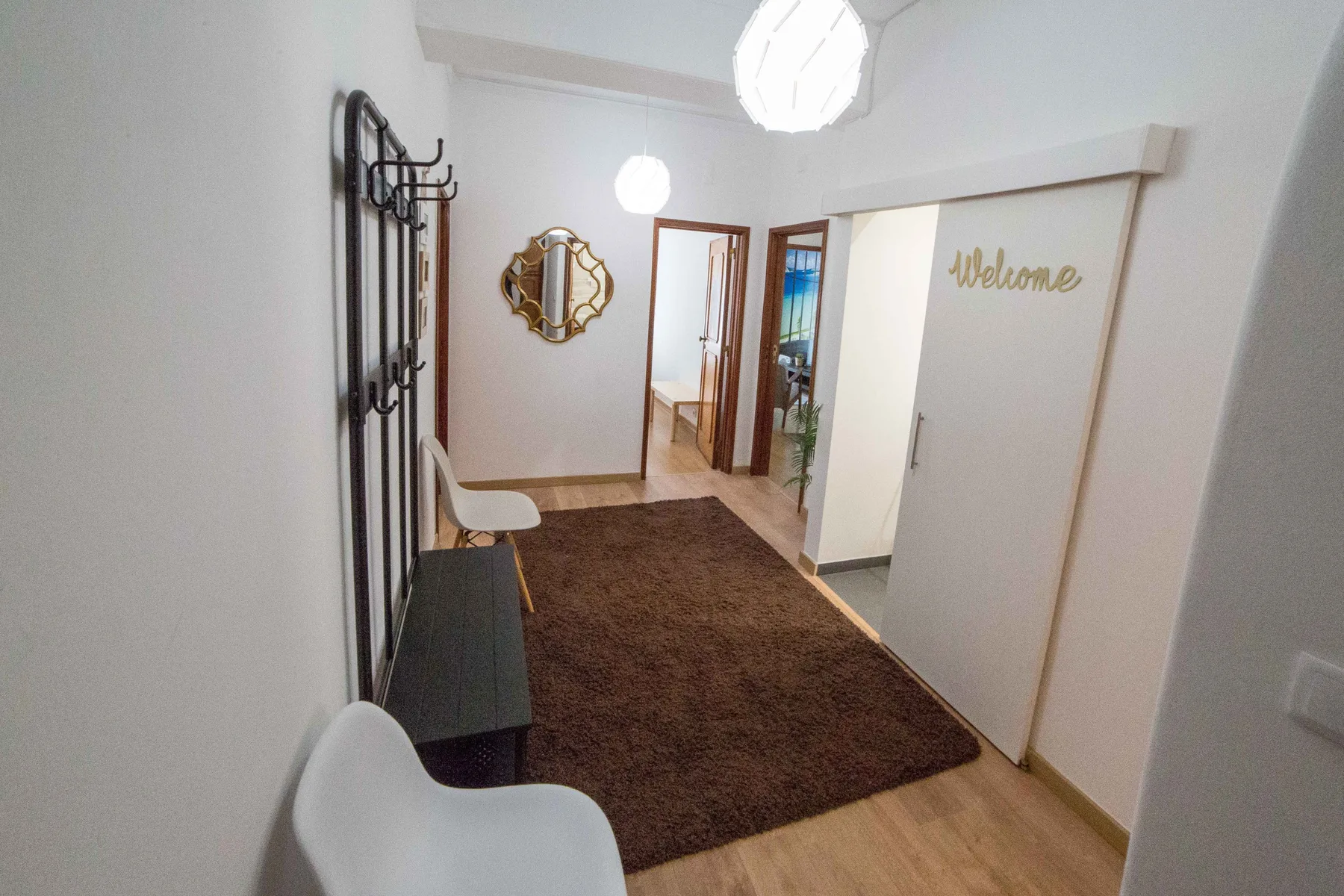 Un recibidor con una alfombra marrón, un espejo en la pared y una puerta corrediza.