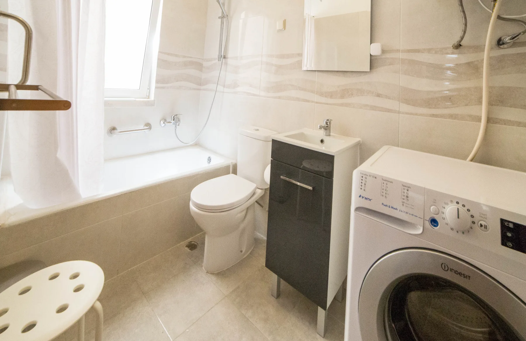 Baño con bañera, inodoro, lavabo y lavadora.